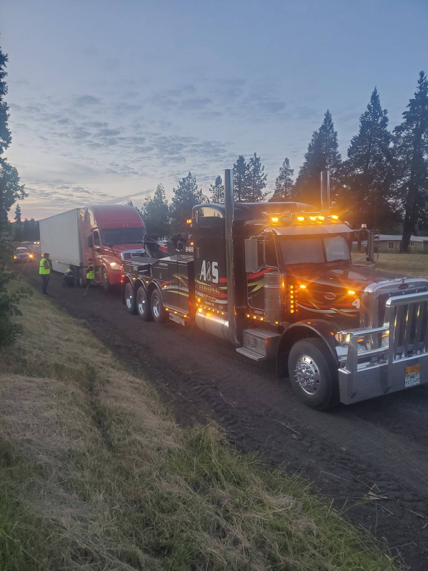 A&S heavy wrecker recovering a semi at dusk